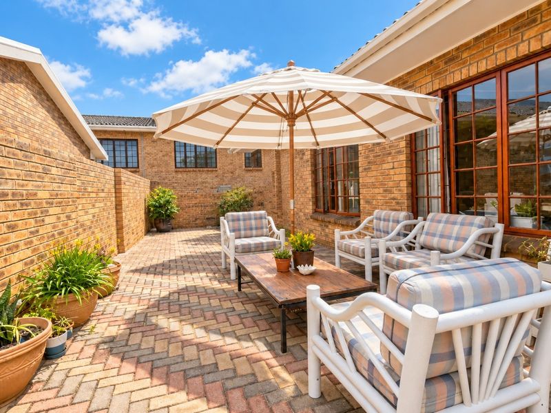A private, paved outdoor patio area featuring face brick walls and timber-framed glass doors, providing a comfortable space for outdoor relaxation.