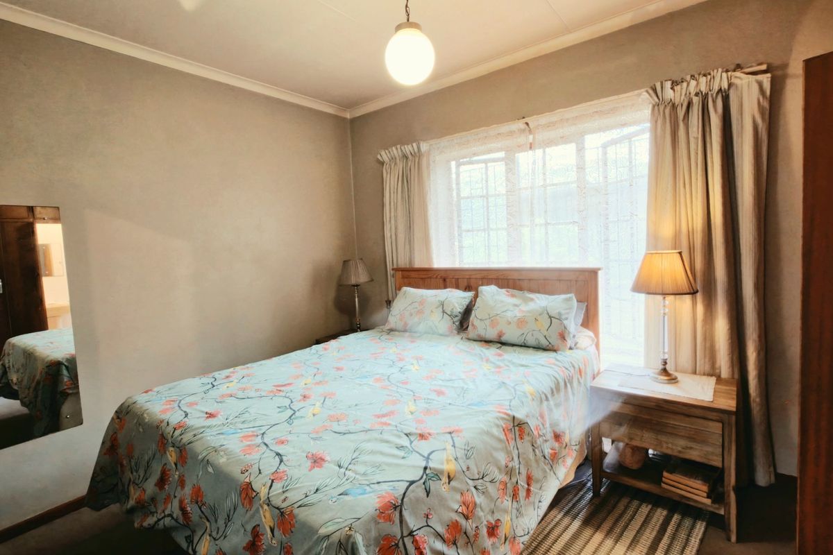 A functional bedroom featuring a built-in cupboard, large window with security bars, and neutral wall finishes.