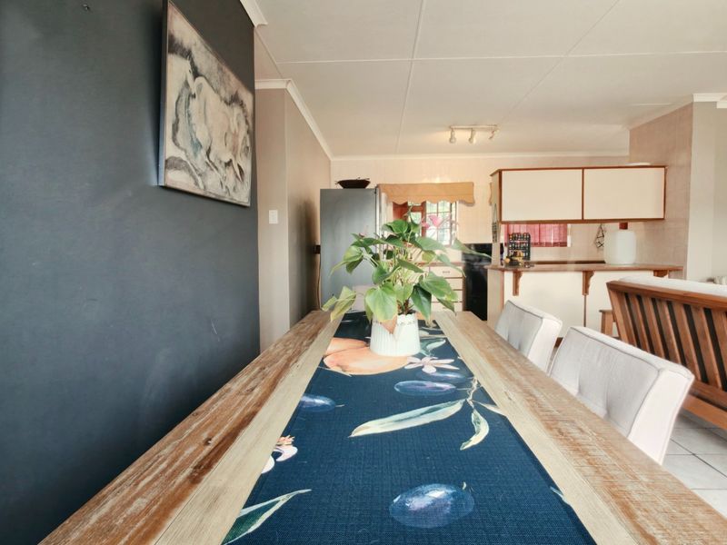Open-plan living and dining area featuring tiled flooring and a functional kitchen with breakfast bar, creating a connected and versatile living space.