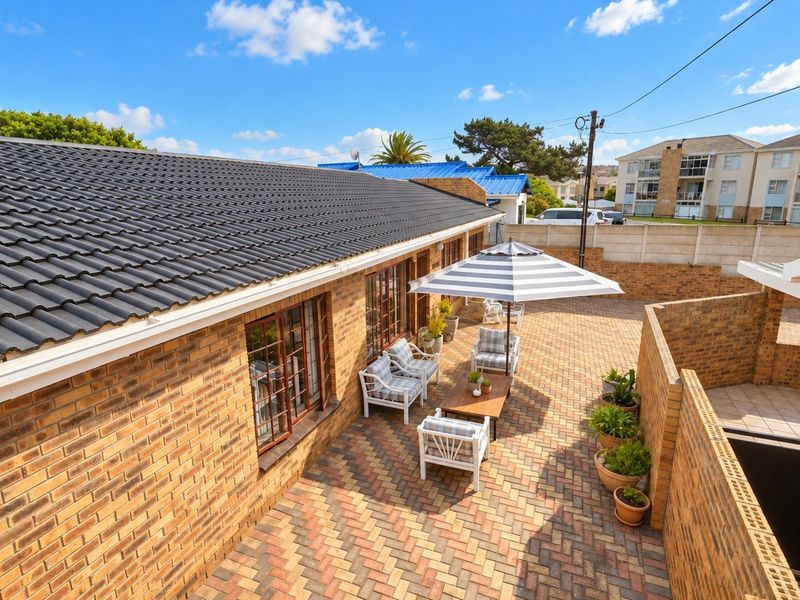 A well-maintained rear courtyard featuring brick paving, enclosed by brick boundary walls, with access to the main dwelling via timber-framed windows.