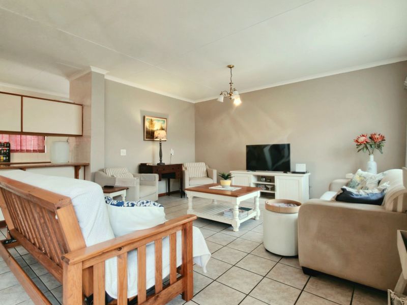 An open-plan living area featuring tiled flooring and a connected kitchen space with built-in cabinetry and a breakfast bar.
