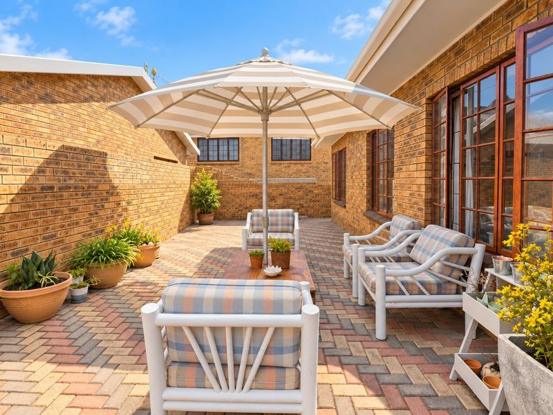 A private, paved outdoor patio area enclosed by face brick walls, featuring timber-framed windows and direct access to the main dwelling.