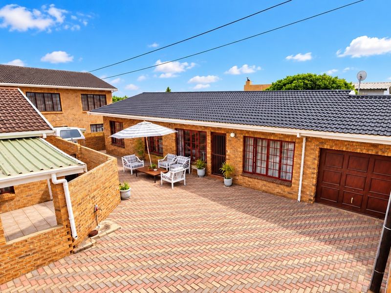 A well-maintained rear courtyard featuring extensive brick paving, a tiled roof structure, and a secure garage entrance.