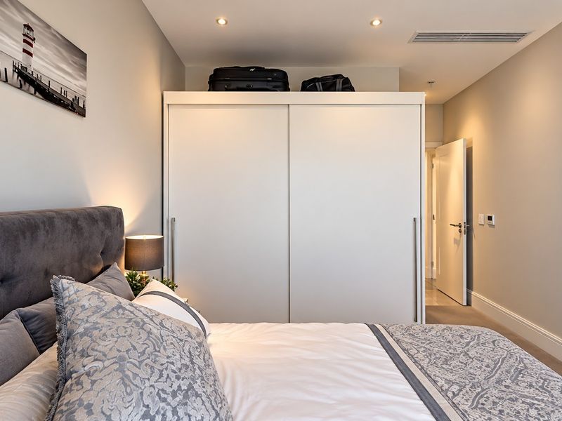 A well-maintained bedroom featuring a large built-in sliding door wardrobe, recessed downlighting, and integrated ducted air conditioning.