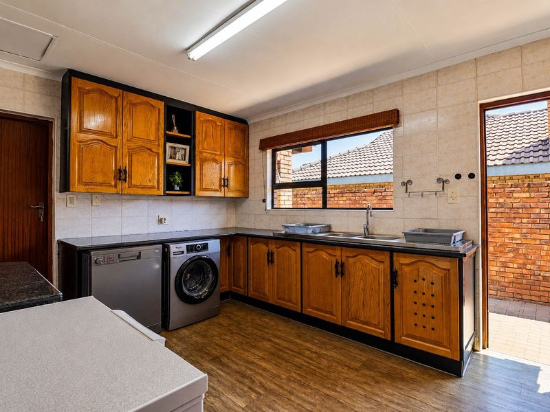 Functional kitchen featuring wooden cabinetry, laminate countertops, tiled backsplash, and direct access to an outdoor paved area.