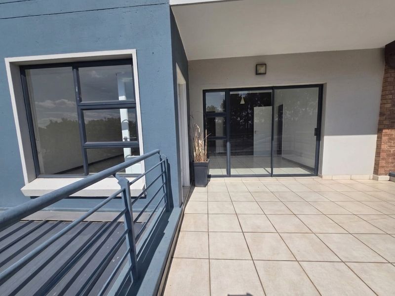 A spacious, tiled balcony featuring modern aluminium sliding doors and a secure metal balustrade, offering a clean and well-maintained outdoor living space.