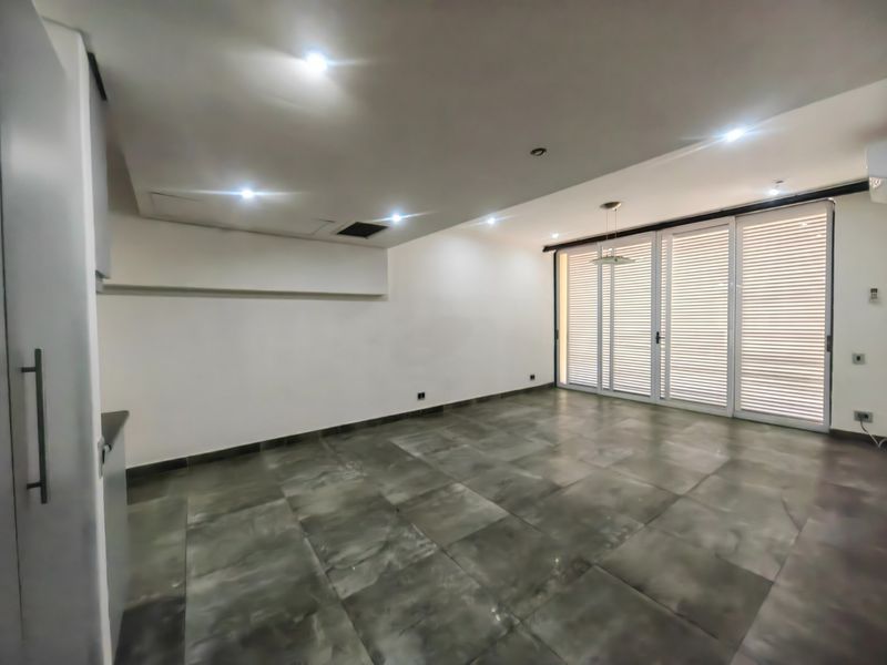 Spacious open-plan living area featuring large format floor tiles, recessed lighting, and expansive sliding glass doors leading to an outdoor space.