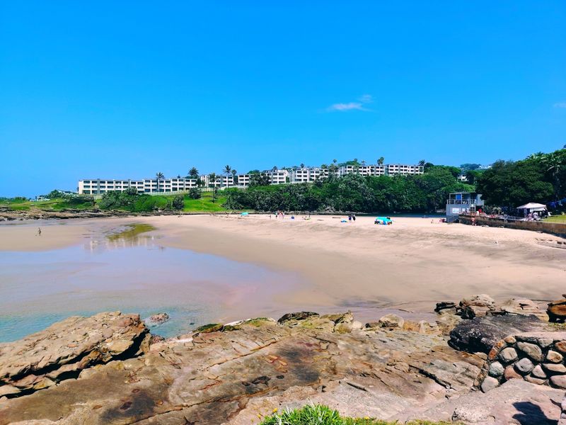 A scenic view of the sandy beach and rocky coastline, showcasing the natural coastal environment surrounding the property.