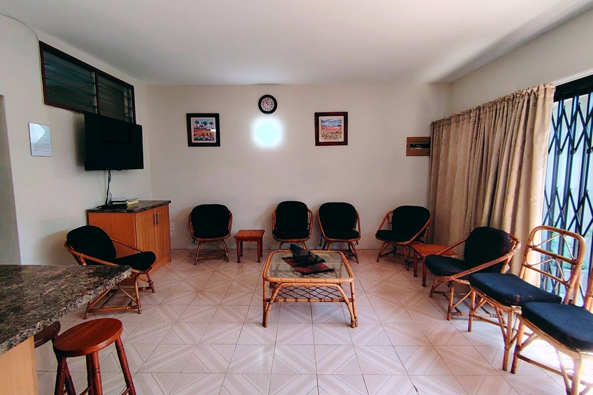A spacious living area featuring tiled flooring, built-in cabinetry, and a granite breakfast bar, with direct access to an outdoor area via a security gate.