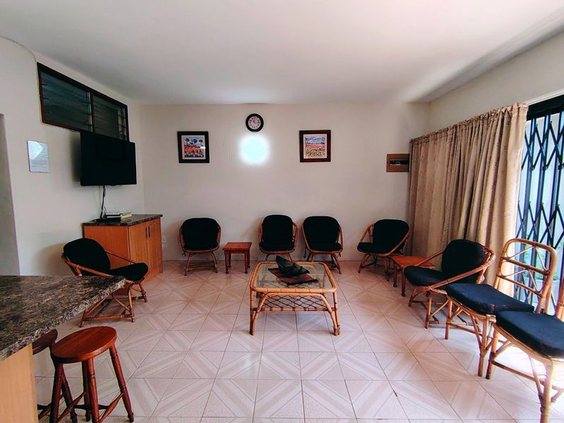 A spacious living area featuring tiled flooring, built-in cabinetry, and a granite breakfast bar, with direct access to an outdoor area via a security gate.