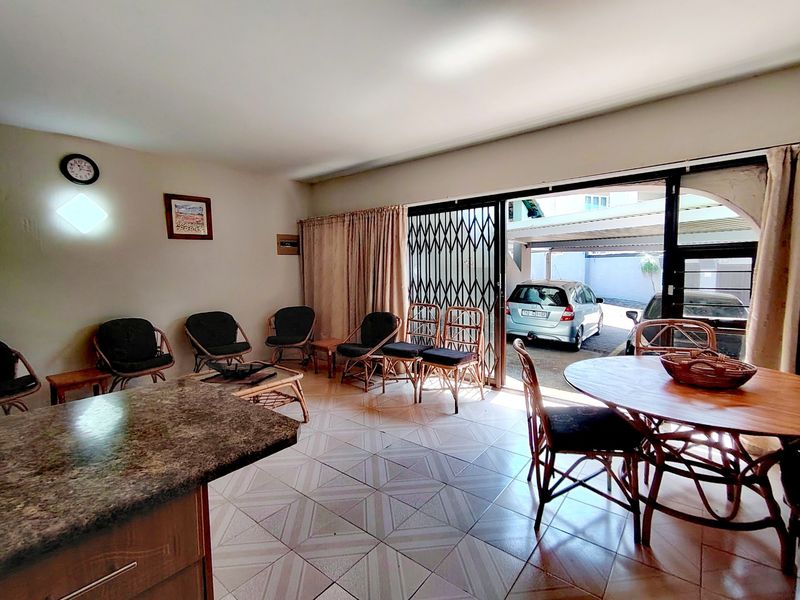 Open plan living and dining area featuring tiled flooring and direct access to the exterior through a sliding glass door with security gate.