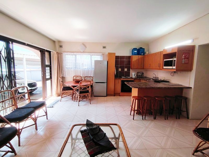 Open-plan living and kitchen area featuring tiled floors, built-in cabinetry, and direct access to an outdoor patio through sliding glass doors.