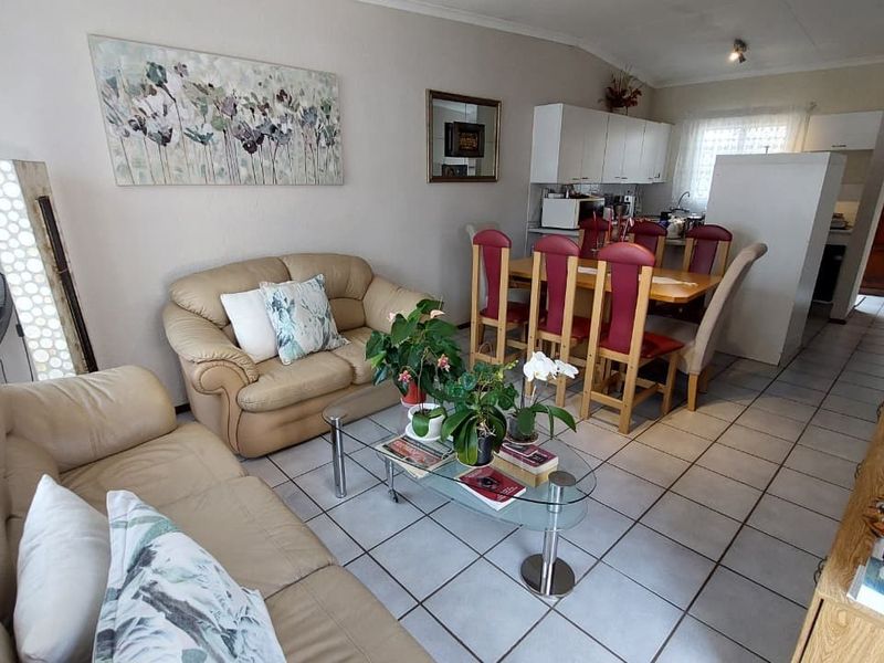 Open-plan living and dining area featuring tiled flooring and a functional kitchen space with built-in cabinetry.