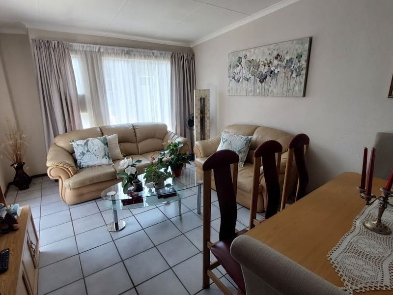 Open plan living and dining area featuring neutral tiled flooring and coved ceilings, providing a functional and well-lit space for daily living.