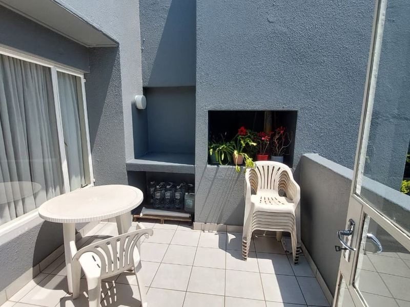 A private balcony featuring a built-in braai area, tiled flooring, and direct access through a sliding door.