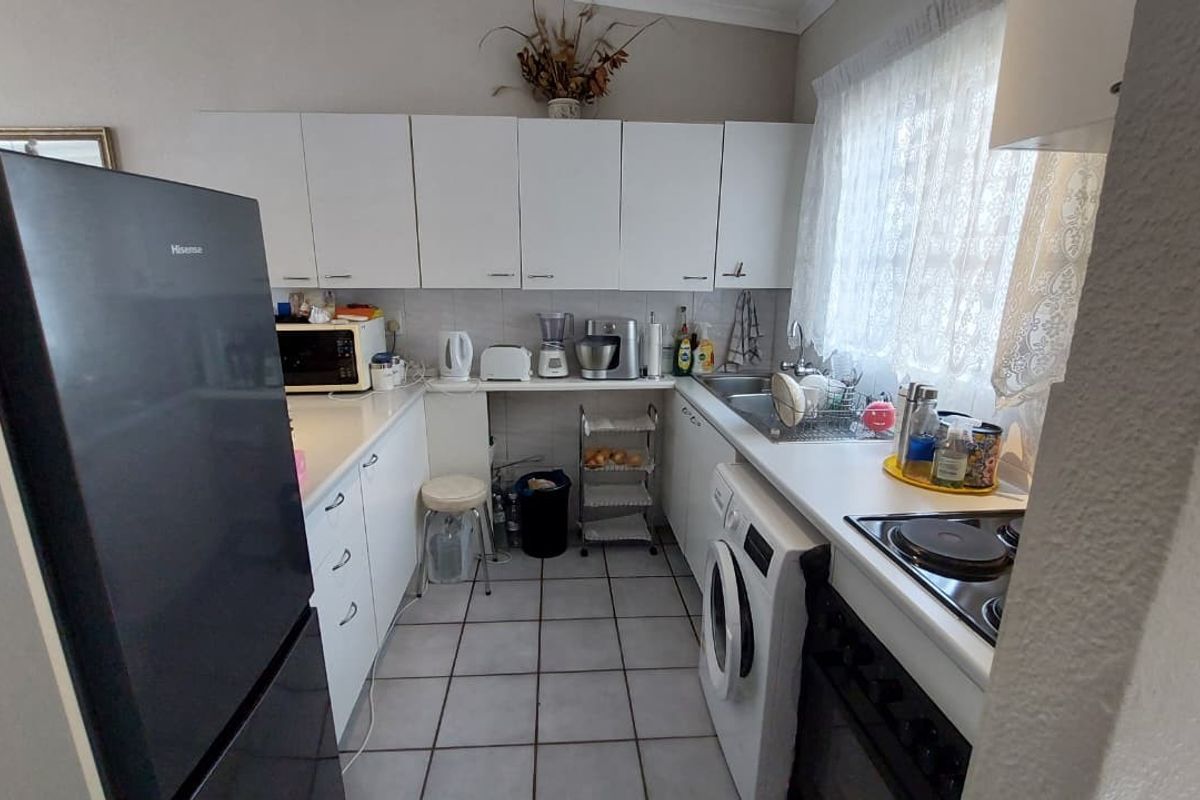 A functional kitchen featuring white cabinetry, laminate countertops, a stainless steel sink, and integrated electric cooking appliances with tiled flooring.