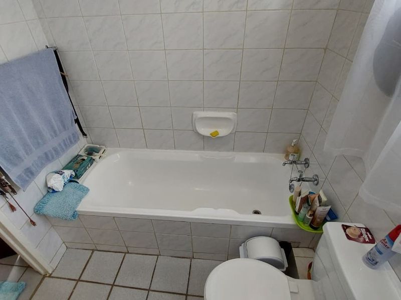 A functional bathroom featuring a standard bathtub, toilet, and tiled finishes throughout, offering a practical layout for daily use.