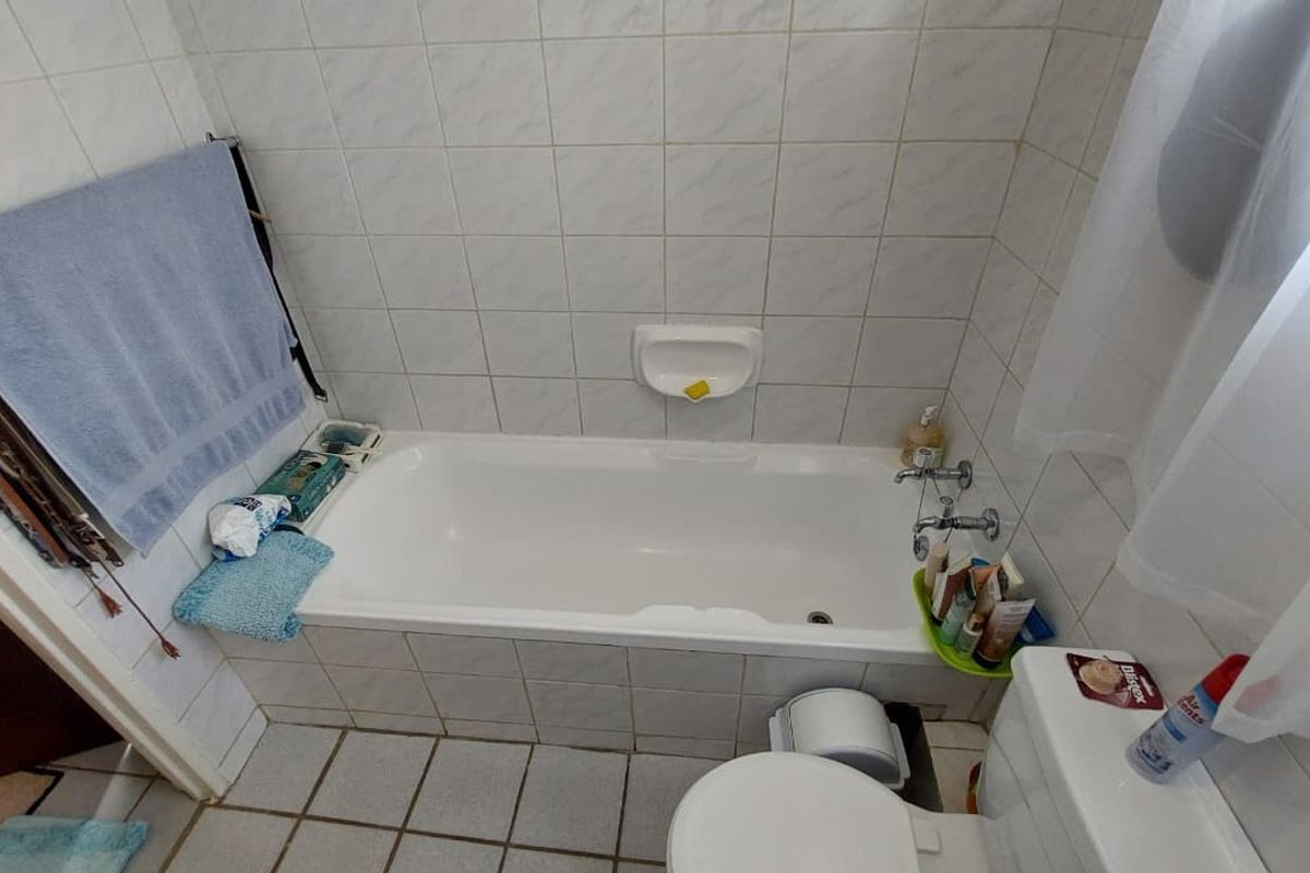 A functional bathroom featuring a standard bathtub, toilet, and tiled finishes throughout, offering a practical layout for daily use.