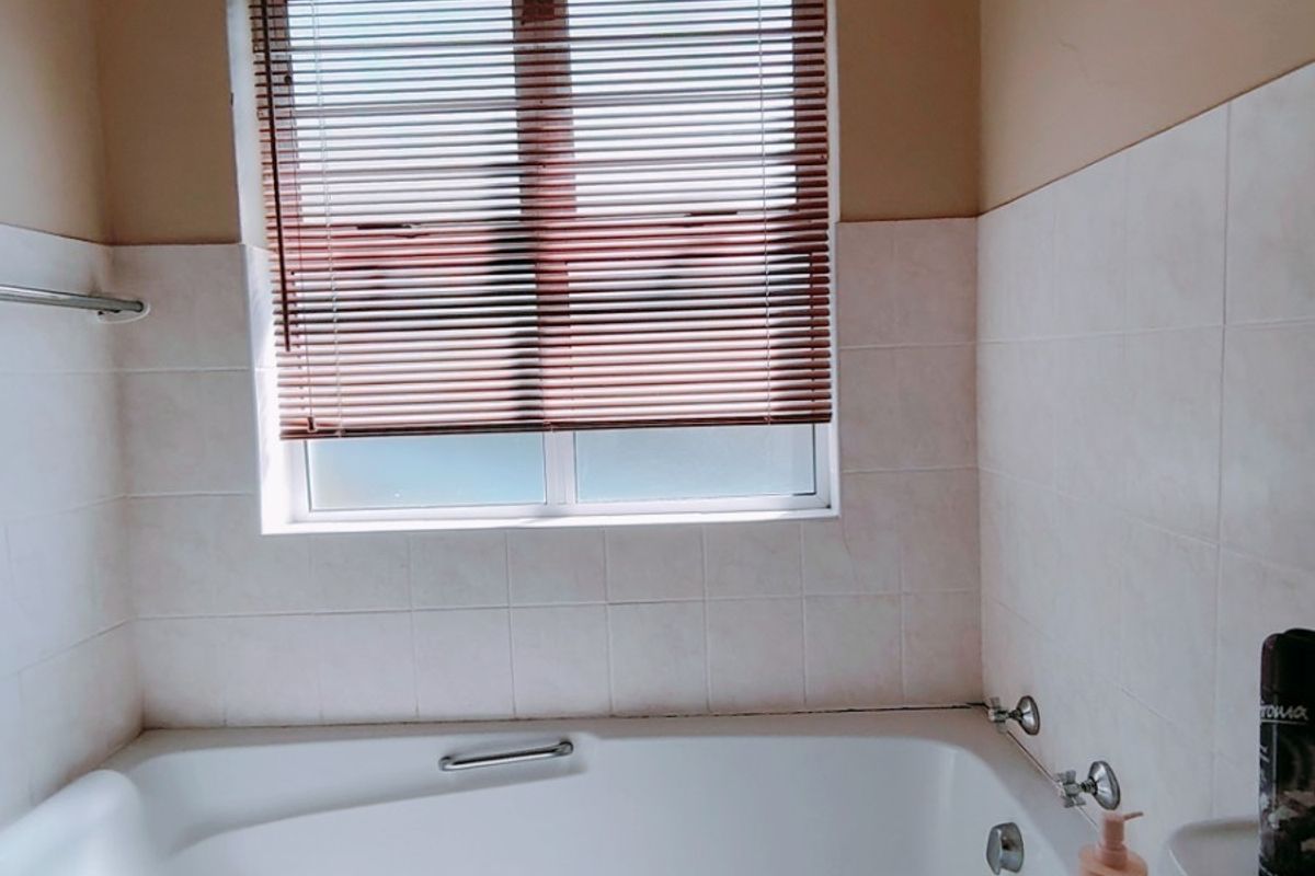 A functional bathroom featuring a built-in bathtub, tiled splashbacks, and an extractor fan, providing a clean and practical space.