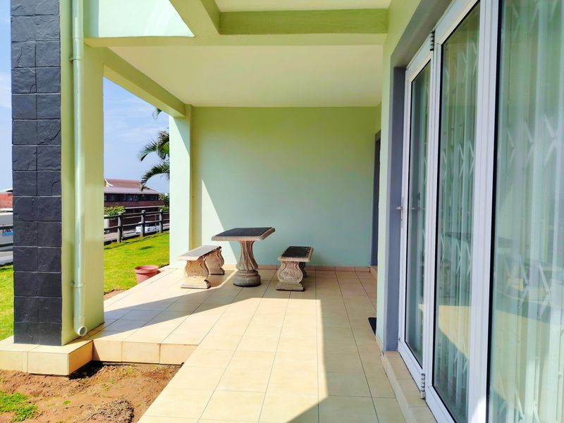 A spacious covered patio featuring tiled flooring and sliding glass door access, offering a pleasant outdoor area for relaxation.