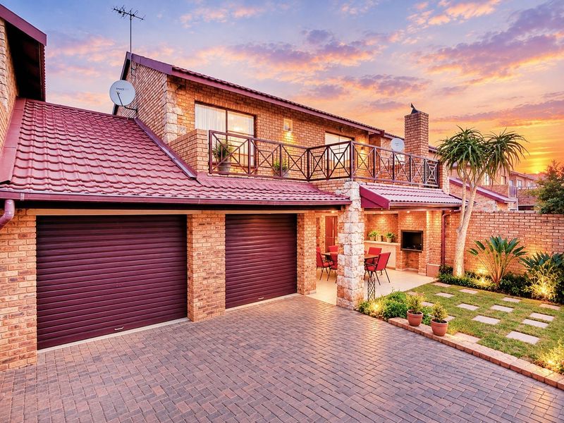 A well-maintained double-story brick home featuring a double garage, a spacious balcony, and a covered patio area with a built-in braai.