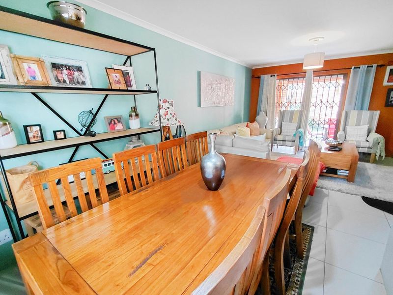 An open-plan living and dining area featuring tiled flooring, a sliding door with security gate, and a light-filled layout.