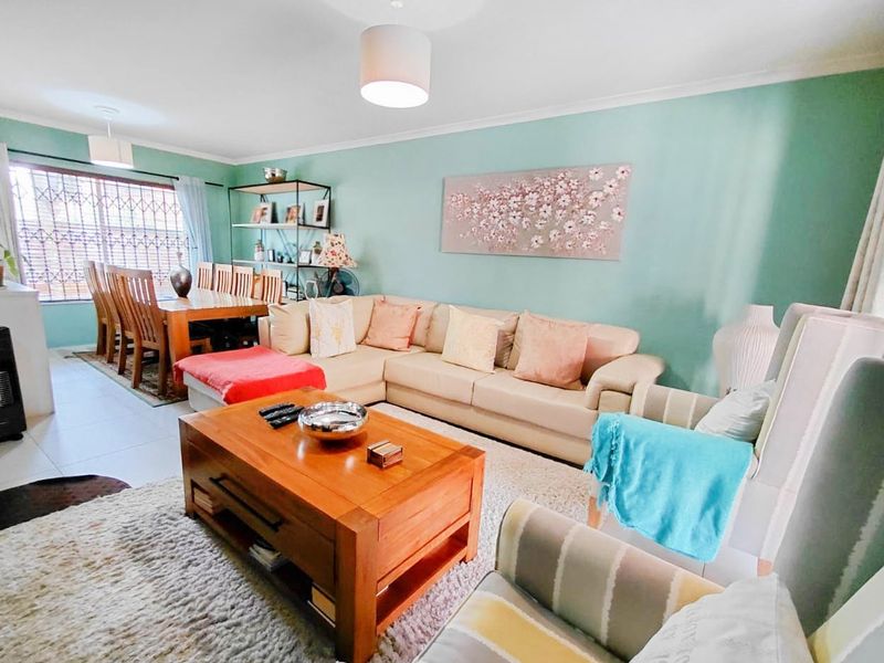Spacious open-plan living and dining area featuring tiled flooring, neutral wall tones, and security bars on the windows.