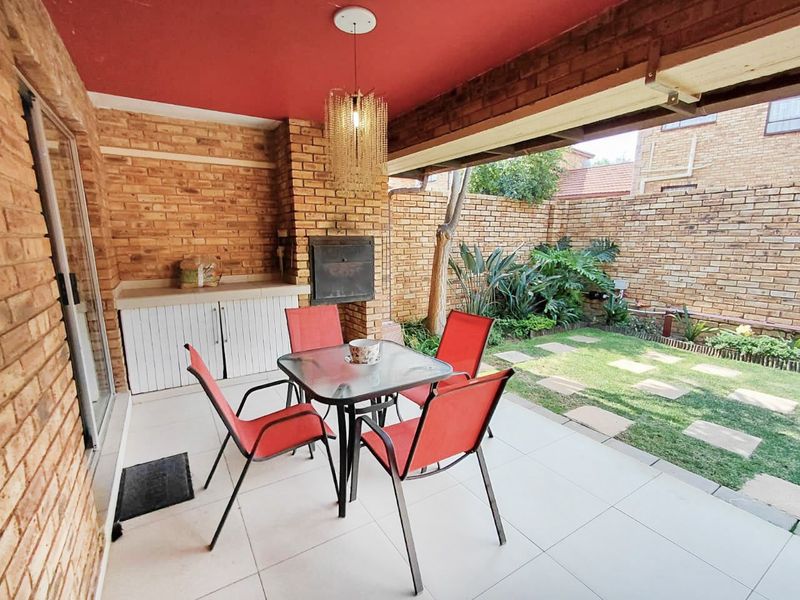 Covered patio area featuring a built-in braai, brick wall finishes, and tiled flooring, overlooking a private garden space.