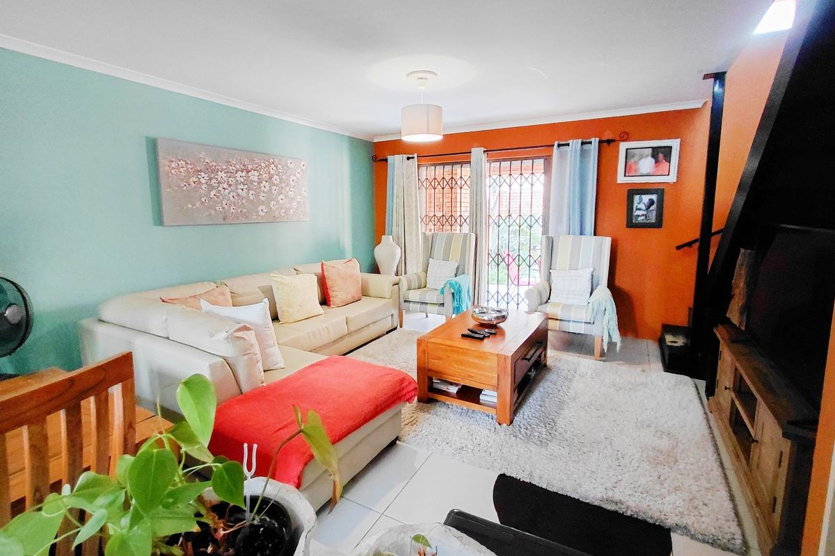 A bright living room featuring tiled flooring, a sliding door with a security gate, and vibrant accent walls.