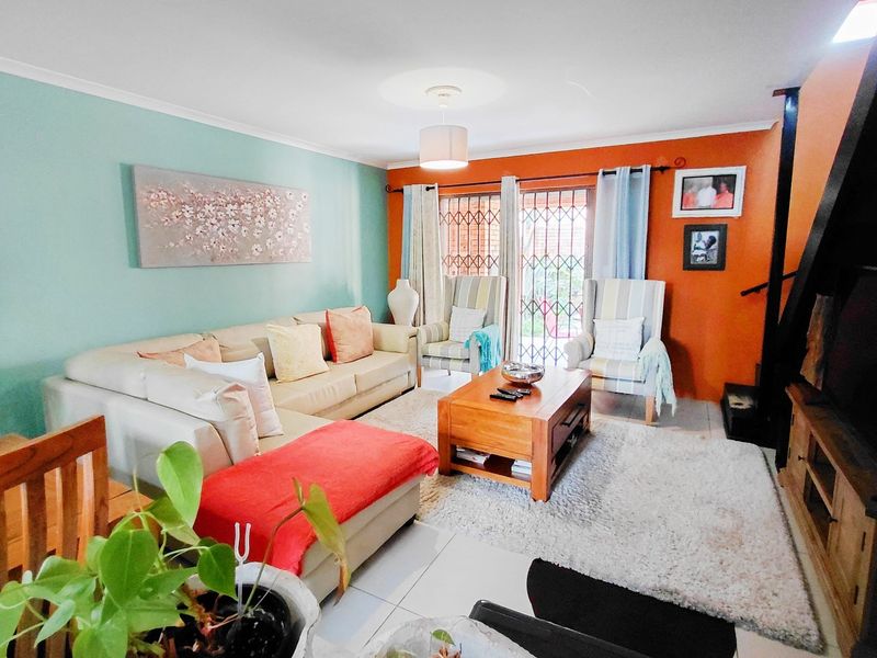 A bright living room featuring tiled flooring, a sliding door with a security gate, and vibrant accent walls.