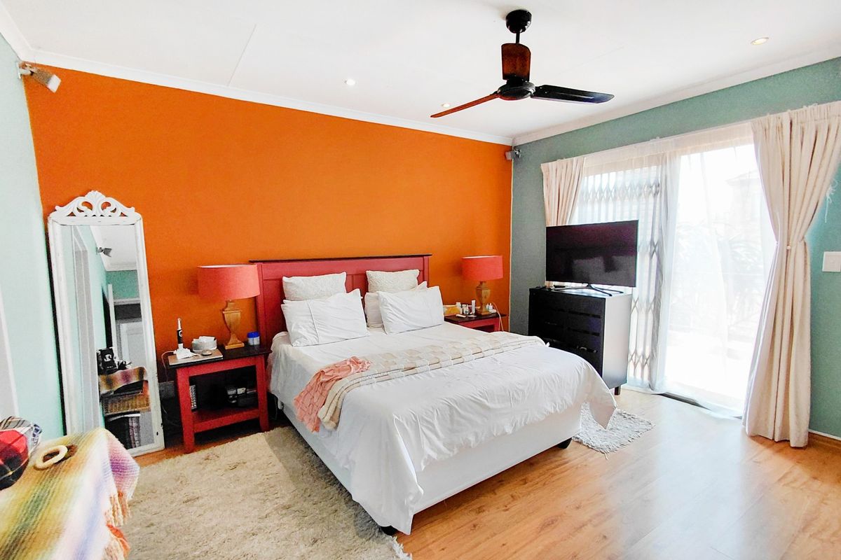 A spacious bedroom featuring laminate flooring, a ceiling fan, and a sliding glass door providing access to the exterior.