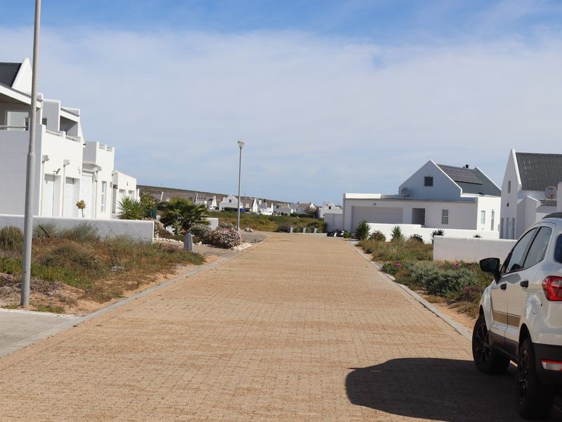 A view of the paved residential street and surrounding coastal-style homes within the estate.