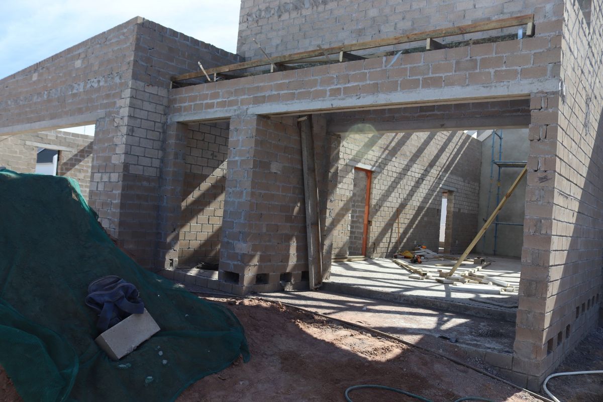 A rear view of a residential property currently under construction, featuring exposed concrete block walls and an unfinished structural frame.