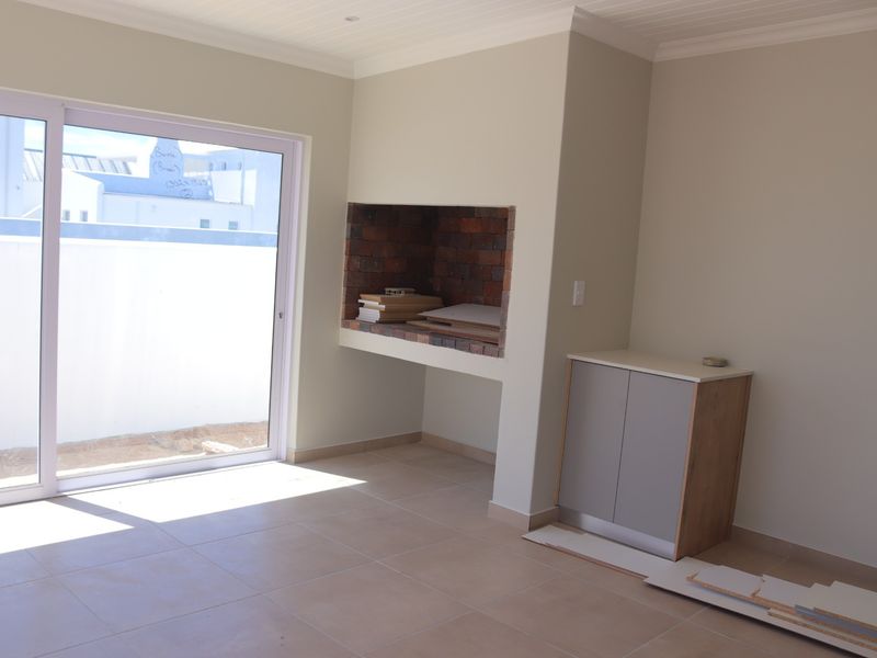 Bright living area featuring a built-in brick fireplace, tiled flooring, and a large sliding glass door providing access to the exterior.