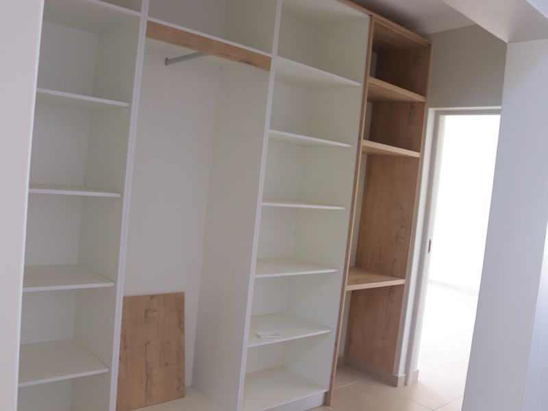 A modern walk-in closet or bedroom storage area featuring custom built-in shelving and hanging space with a clean, contemporary finish.