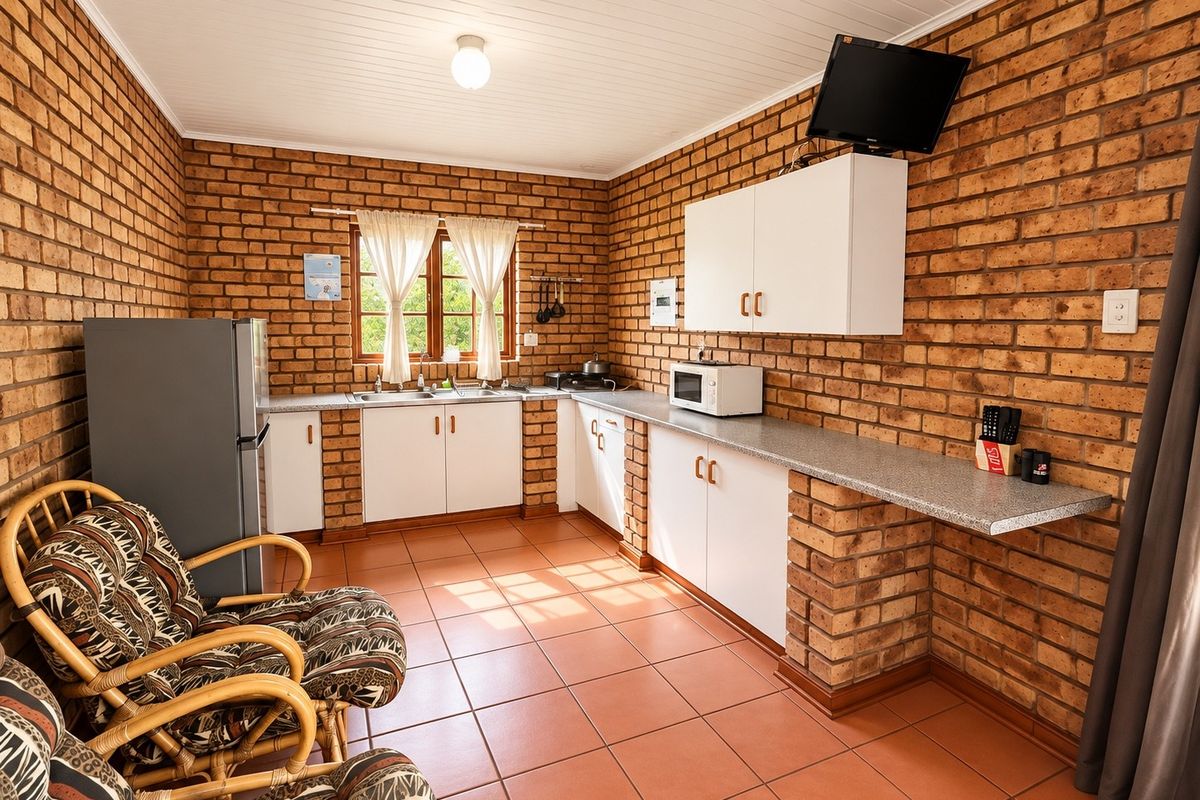 A rustic kitchen featuring exposed brick walls, tiled flooring, and functional built-in cabinetry with laminate countertops.