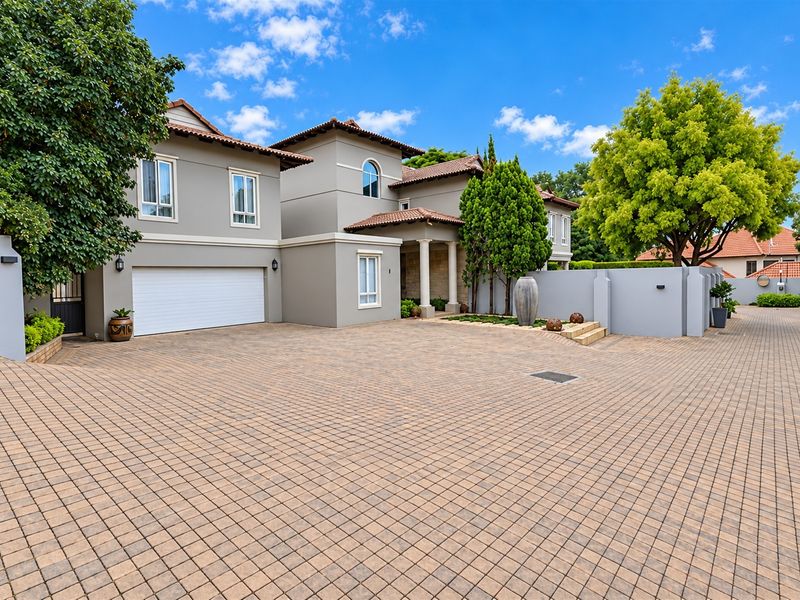 A well-maintained double-story residence featuring a spacious paved driveway, integrated double garage, and a covered entrance with a tiled roof.