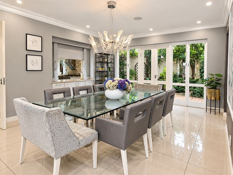 Elegant dining room featuring polished tile floors, crown molding, recessed lighting, and direct access to the garden through glass-paned french doors.