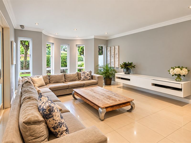 A bright and modern living room featuring large windows, tiled flooring, a floating media console, and elegant crown molding.