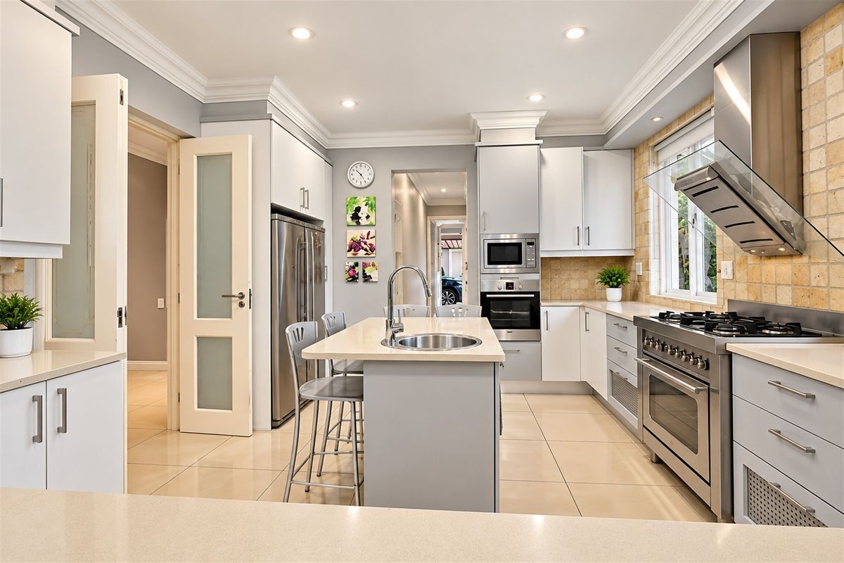 Modern kitchen featuring a central island with sink, stone countertops, stainless steel appliances, gas cooktop, and elegant crown molding.