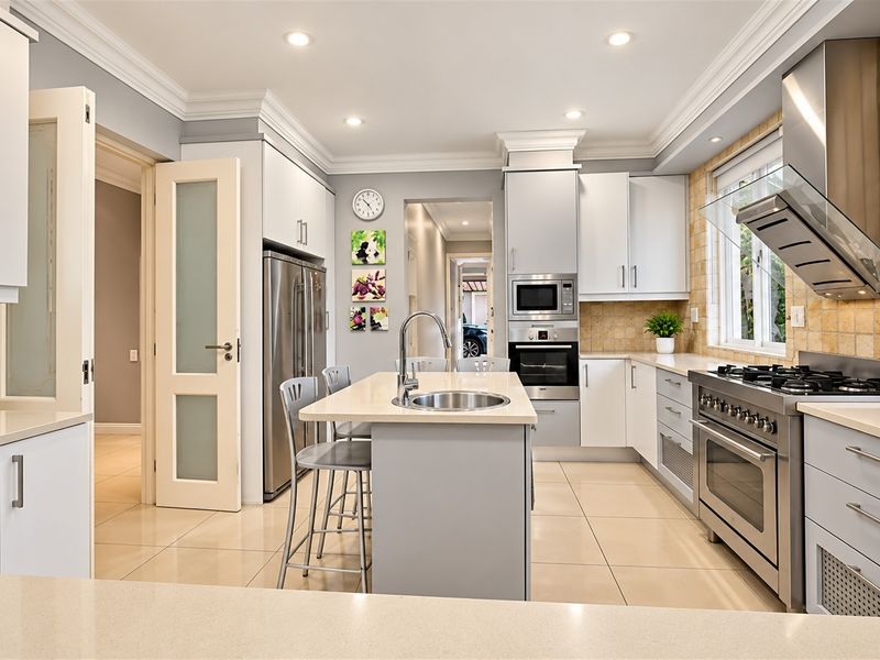 Modern kitchen featuring a central island with sink, stone countertops, stainless steel appliances, gas cooktop, and elegant crown molding.