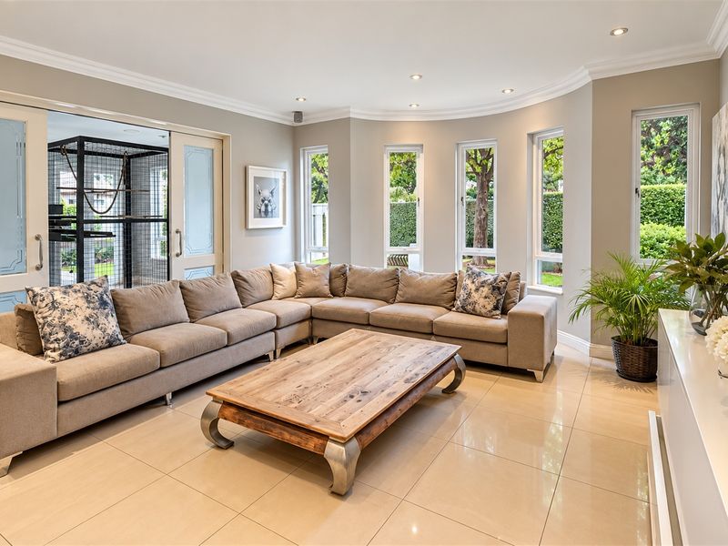 A bright and spacious living room featuring large windows, polished porcelain floor tiles, recessed lighting, and elegant sliding doors leading to an outdoor area.