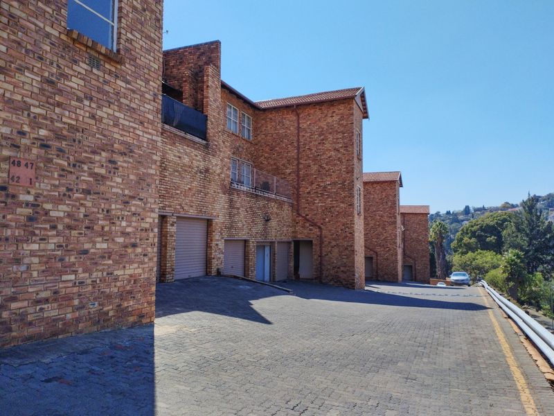 Exterior view of a multi-story face brick apartment complex featuring paved driveway access and integrated garage units.