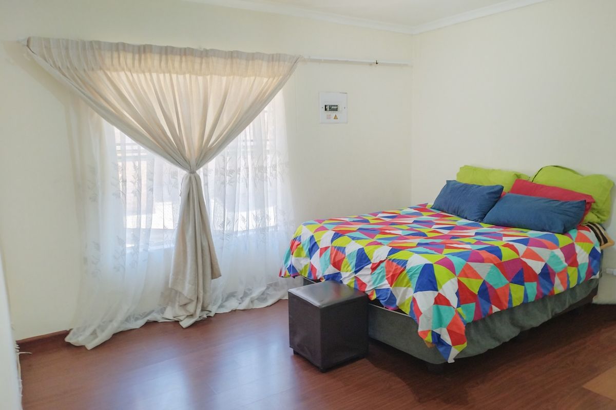 A bedroom featuring laminate flooring, neutral wall finishes, and a visible electrical distribution board.