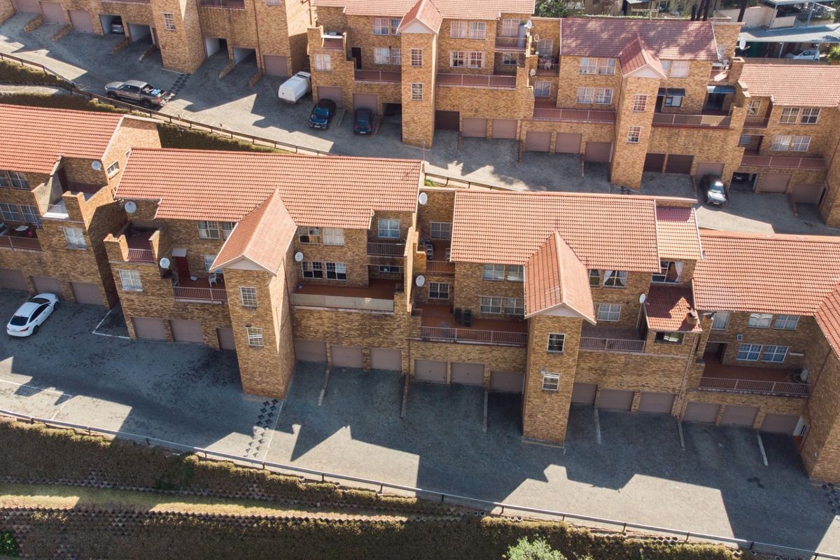 Aerial view of a multi-unit apartment complex featuring face-brick construction, tiled roofing, integrated garages, and private balconies.