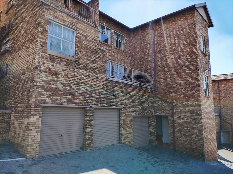 Exterior view of a multi-story apartment building featuring a face brick facade, three garage doors, and upper-level balconies.