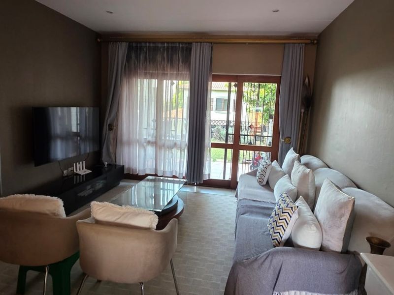 A comfortable living room featuring tiled flooring, recessed lighting, and a sliding glass door providing access to the outdoor area.