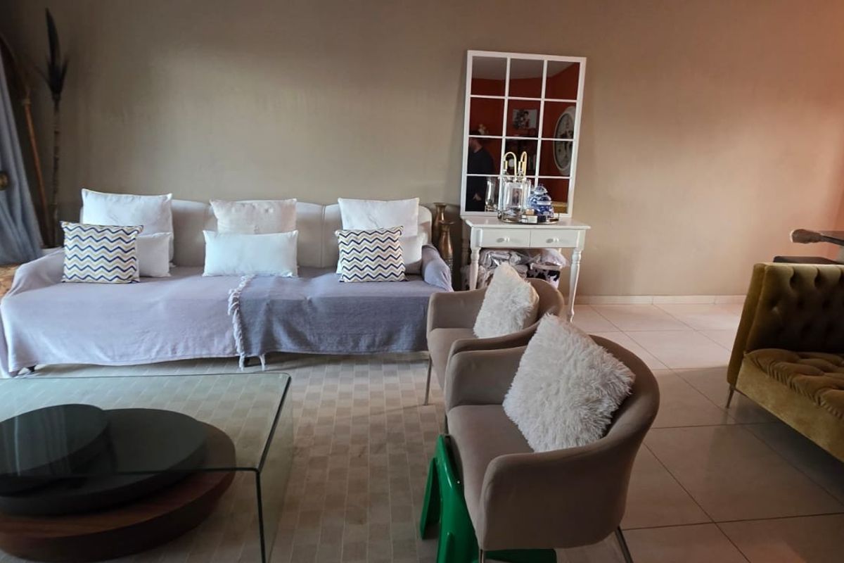 A comfortable living room featuring tiled flooring and a large sliding glass door providing access to the outdoor area.