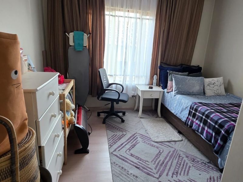 A functional bedroom featuring laminate flooring and large window with curtain tracks, providing natural light to the space.