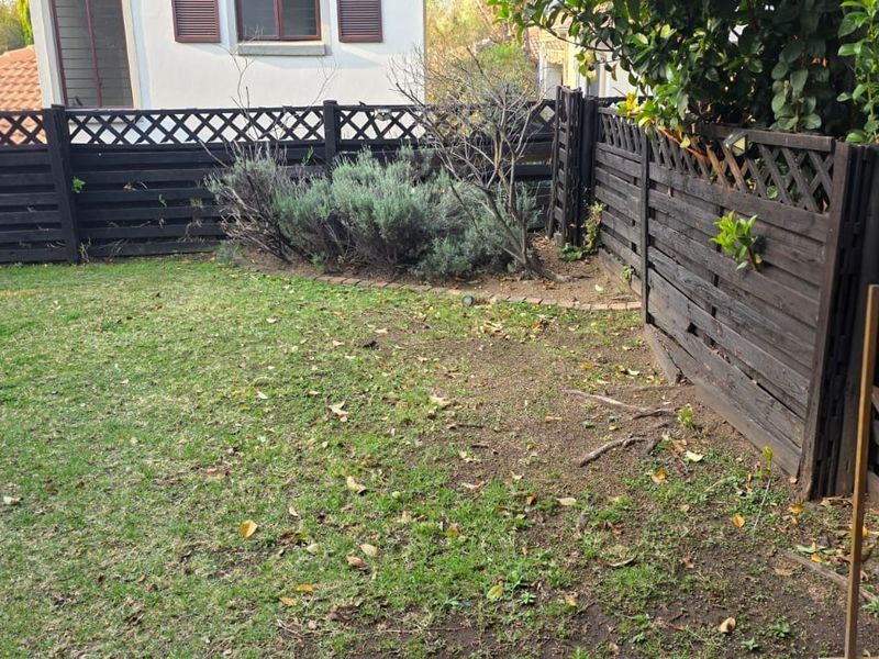A private garden area featuring established lawn, brick edging, and timber lattice fencing, offering a blank canvas for landscaping improvements.